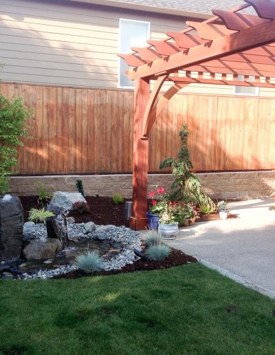 A Greenhaven Landscapes design customer's Vancouver WA wood arbor over concrete patio and bubbler water feature
