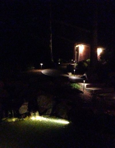 A Greenhaven Landscapes design customer's Vancouver WA gravel walkway at night with outdoor lighting and up lights on trees