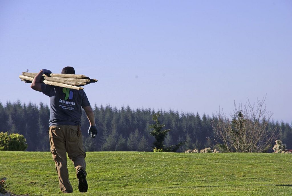A Greenhaven Landscapes landscape maintenance employee moves fence posts on a Vancouver WA property