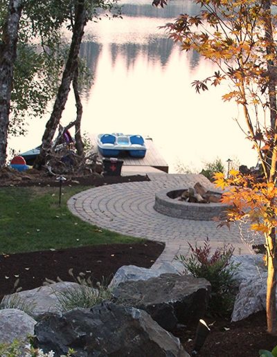 A Greenhaven Landscapes design customer's Vancouver WA waterfront home with stone walkway path leading to stone patio with furniture and dock