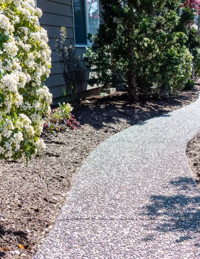 A Greenhaven Landscapes design customer's Vancouver WA back yard with stone walkway, and beautiful greenery lining the path