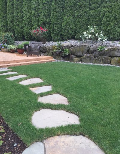 A Greenhaven Landscapes landscape maintenance customer's Vancouver WA back yard with lush green grass and stone stepping stones