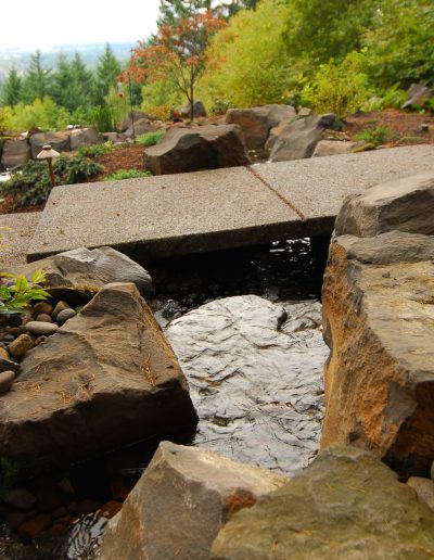 A Greenhaven Landscapes-designed water feature - a Vancouver WA backyard waterfall with stone bridge pathway