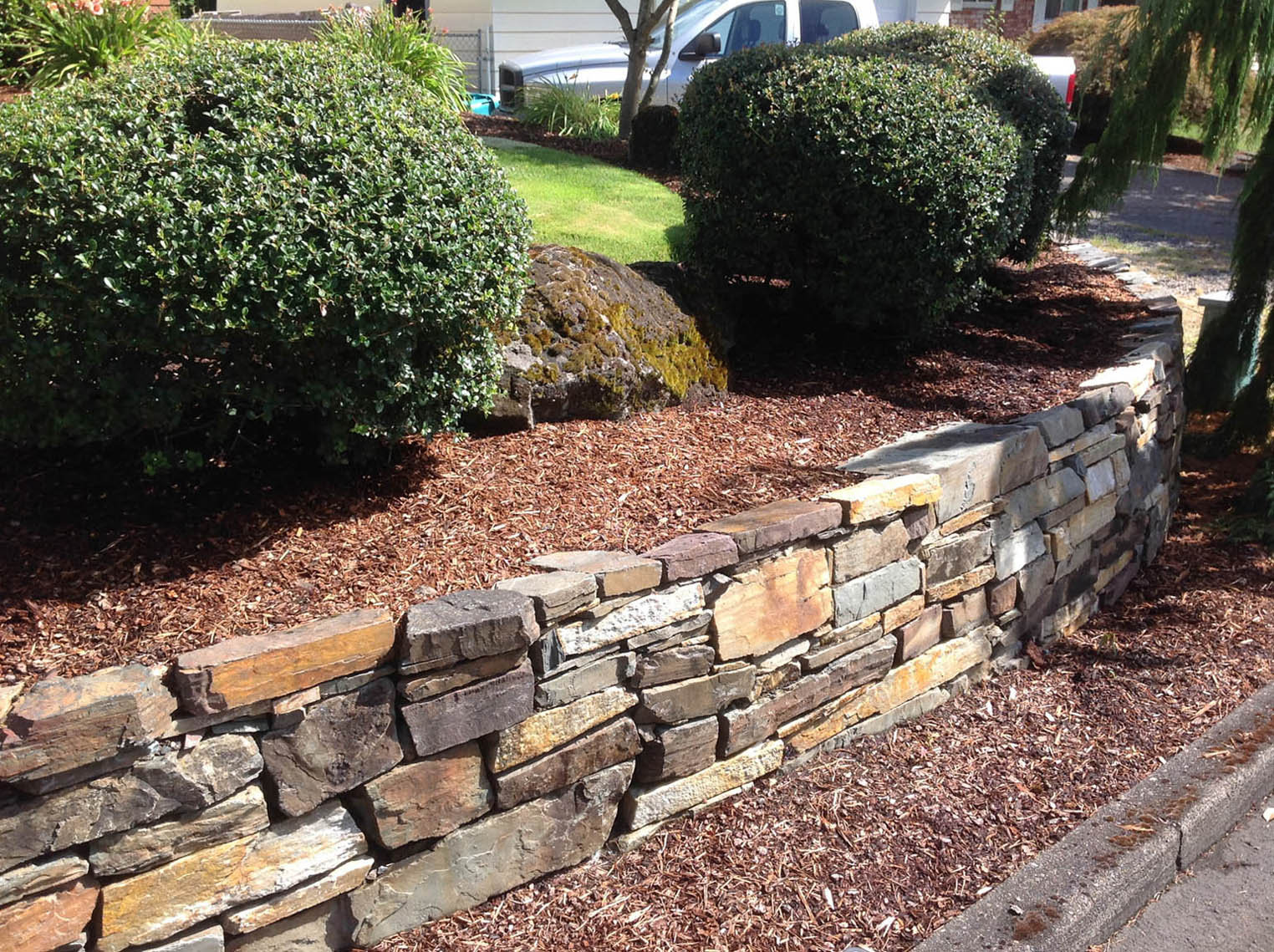 A Greenhaven Landscapes-designed customer's Vancouver WA masonry retaining wall and shrubbery