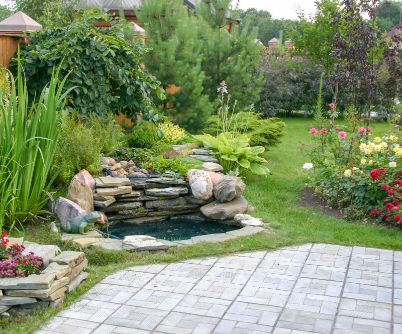 landscaped yard with flowers and small pond