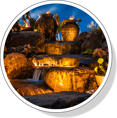 a pond glows at night with lighting by Greenhaven Landscapes