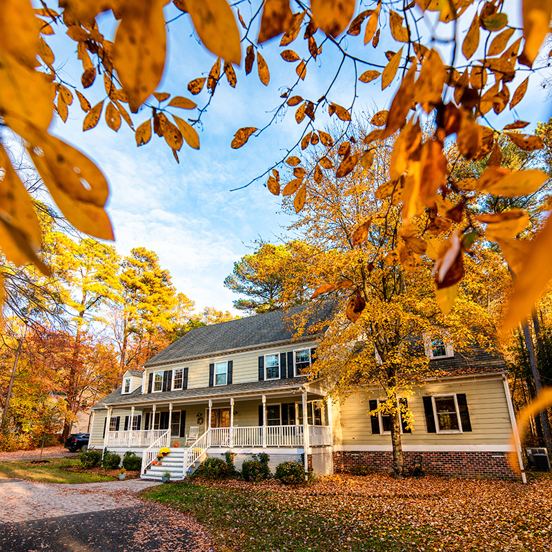the front exterior of a house in autumn surrounded by trees changing color the front exterior of a house in autumn surrounded by trees changing color