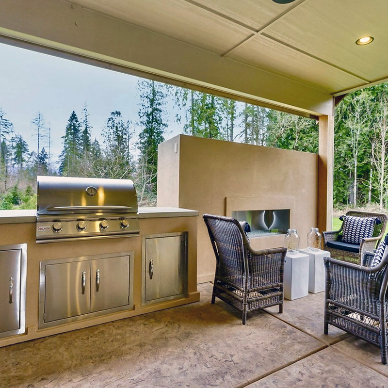 a covered outdoor fireplace and barbecue space by Greenhaven Outdoor Living